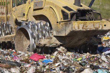 Açık hava atık sahasında çöp öğüten ağır makineler. İsraf.