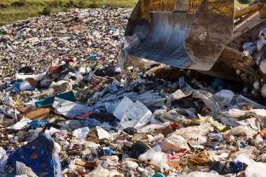 Açık hava atık sahasında çöp öğüten ağır makineler. İsraf.