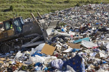 Açık hava atık sahasında çöp öğüten ağır makineler. İsraf.