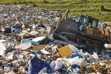 Heavy machinery shredding garbage in an open air landfill. Waste