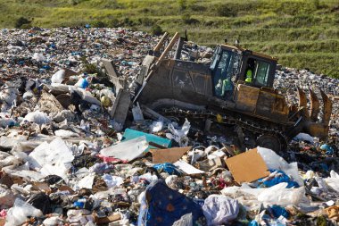 Açık hava atık sahasında çöp öğüten ağır makineler. İsraf.