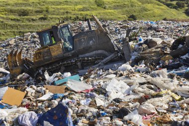 Açık hava atık sahasında çöp öğüten ağır makineler. İsraf.