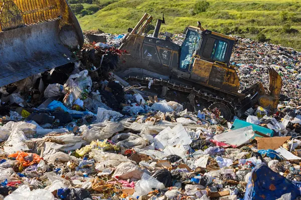 Heavy machinery shredding garbage in an open air landfill. Waste