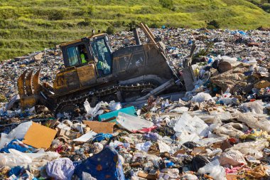Açık hava atık sahasında çöp öğüten ağır makineler. İsraf.