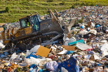Heavy machinery shredding garbage in an open air landfill. Waste