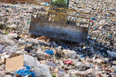 Heavy machinery shredding garbage in an open air landfill. Waste