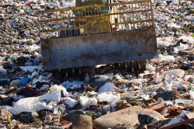 Açık hava atık sahasında çöp öğüten ağır makineler. İsraf.
