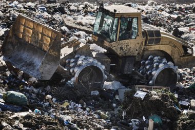 Heavy machinery shredding garbage in an open air landfill. Waste