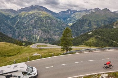 Cyclist in alpine serpentine mountain road. Landmark route in Austria clipart