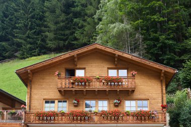 Traditional rustic wooden house decorated with flowers in Austria clipart