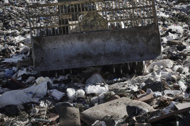 Açık hava atık sahasında çöp öğüten ağır makineler. İsraf.
