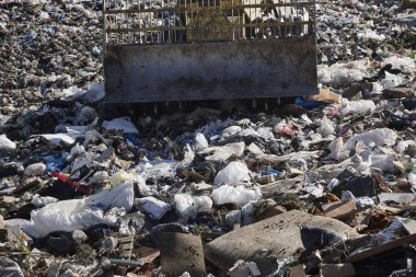 Açık hava atık sahasında çöp öğüten ağır makineler. İsraf.