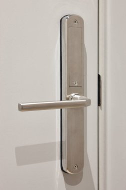 Beyaz bir kapının metal kapı kolu. Otel odası detayı