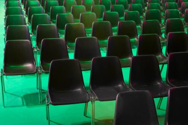 Konferans salonu. Yeşil ışıkla aydınlatılmış sandalyelerle dolu oditoryum