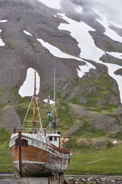 Paslı balıkçı teknesi ve karlı dağ. Siglufjordur köyü. İzlanda