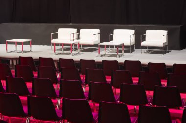 Konferans salonu. Kırmızı ışıkla aydınlatılmış sandalyelerle dolu oditoryum