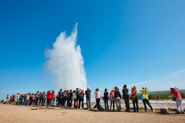 Fotoğraf çeken insanlar. Strokkur gayzeri sıcak su püskürtüyor. İzlanda simgesi