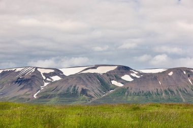 Karlı dağlarla İzlanda manzarası. Bulutlu gökyüzü