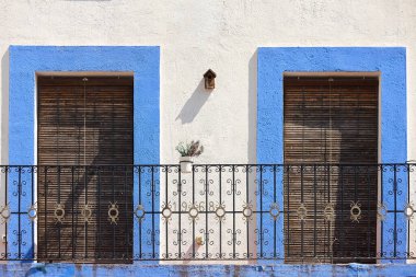 Mavi ve beyaz renkli demir balkonu olan resim gibi bir cephe.