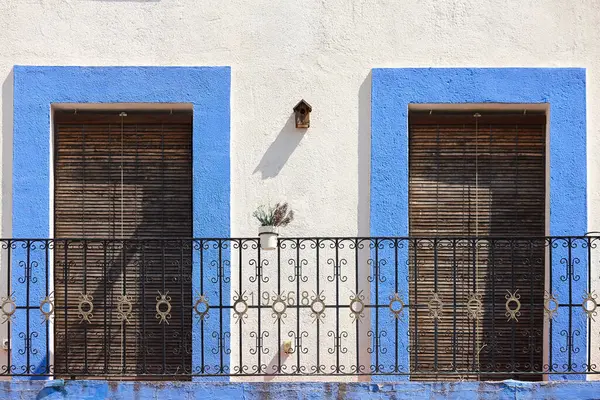 Mavi ve beyaz renkli demir balkonu olan resim gibi bir cephe.