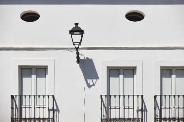 Demirden balkonları ve sokak lambalarıyla bembeyaz ev cephesi. İspanya