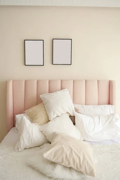 Warm and cozy interior of bedding room space with pink bed, mock up poster frame.