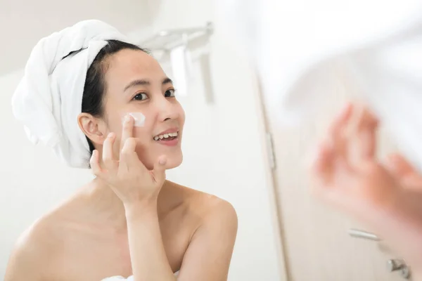 Happy Young Asian Woman Applying Face Lotions While Wearing Towel — Stock Photo, Image