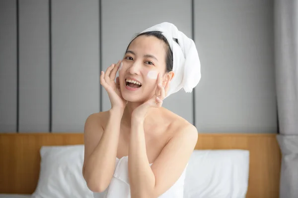 Glückliche Junge Asiatin Trägt Gesichtslotionen Auf Während Sie Ein Handtuch — Stockfoto