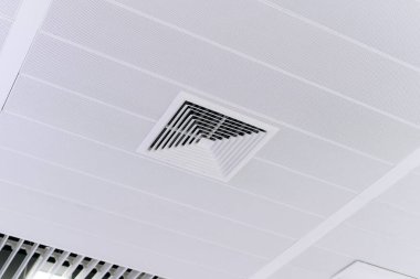 Ev ya da ofis için havalandırma kanalı. Tavana monte edilmiş kaset tipi klima ve beyaz tavanda modern lamba ışığı..