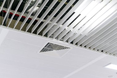 Ev ya da ofis için havalandırma kanalı. Tavana monte edilmiş kaset tipi klima ve beyaz tavanda modern lamba ışığı..
