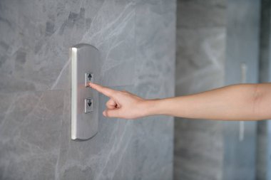 Asansör için düğmeye basan bir kadının kırpılmış eli