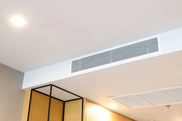 Duct air conditioner for home or office. Ceiling mounted cassette type air conditioner and modern lamp light on white ceiling.