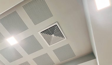 Duct air conditioner for home, hall or office. Ceiling mounted cassette type air conditioner and modern lamp light on white ceiling.