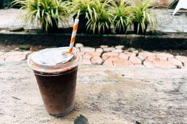 Ice chocolate milk in a clear plastic glass on a wooden cafe table