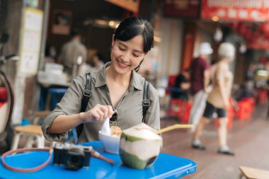 Happy young Asian woman backpack traveler enjoying street food at China town street food market in Bangkok, Thailand.