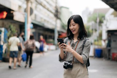 Young Asian woman backpack traveler using mobile phone, enjoying street cultural local place.