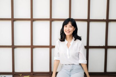 Portrait beautiful young asian woman happiness sitting on wooden grid wall, Happy female is smiling on wooden grid wall