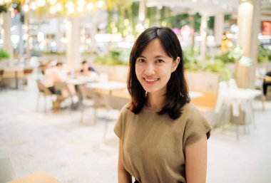 Smiling beautiful asian woman standing in cafeteria at shopping mall.