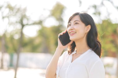 Portrait beautiful young asian woman with smart mobile phone around outdoor nature view in sunny summer day
