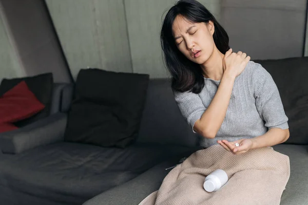 Asian woman has shoulder pain. Female holding painful shoulder with another hand. People with body-muscles problem