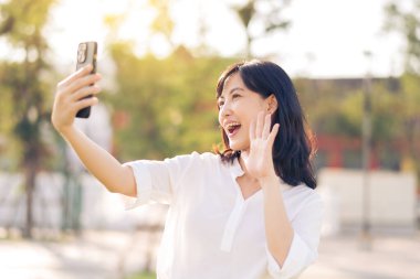Portrait beautiful young asian woman with smart mobile phone around outdoor nature view in sunny summer day