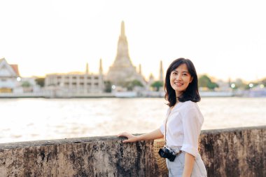 Güzel Asyalı kadının portresi Wat Arun 'da gün batımı manzarasında gülümsüyor, Bangkok, Tayland.
