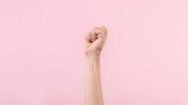 Woman fist fight for human rights and feminist with pink pastel background. Women empowerment, strength, equality and courage concept