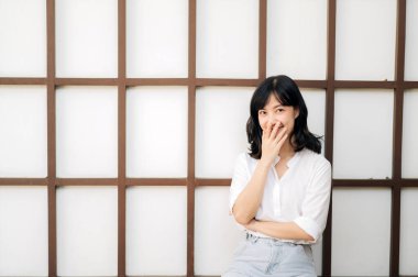 Portrait beautiful young asian woman happiness sitting on wooden grid wall, Happy female is smiling on wooden grid wall