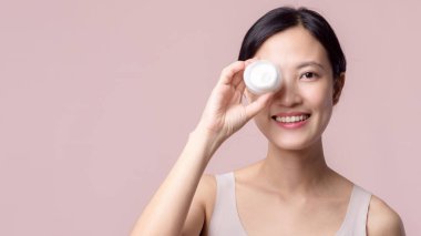Yüz kremi sürmüş Asyalı genç bir kadın sağlıklı doğal cilt makyajında kozmetik nemlendirici. Parlak gülümsemeli kız modeli özenli güzellik ürünü, spa, kozmetoloji.