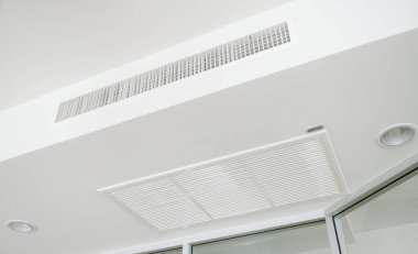 Ceiling mounted cassette type air conditioner and modern lamp light on white ceiling. duct air conditioner for office or home clipart