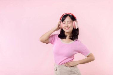 Gülümse güzel model, müzik dinle ve kablosuz kulaklıkla dansın tadını çıkar. Neşeli, neşeli bir genç kadın pembe izole edilmiş arka planda şarkı söylüyor.