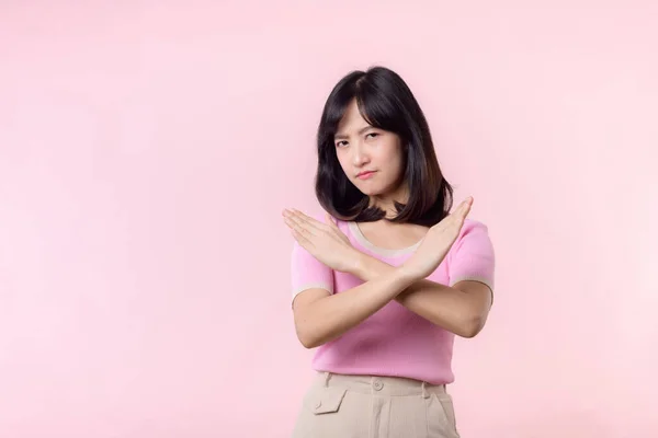 肖像画の若い深刻なアジアの女性の腕のジェスチャーを停止を示す いいえ 間違っ ピンクのパステルスタジオの背景に隔離された拒絶サイン 否定と否定の表現記号の概念 — ストック写真
