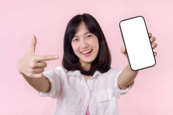 快乐的笑着的亚洲年轻女性推荐展示新的应用程序或移动广告 模仿被粉色背景隔离的智能手机模板 大写字母空白屏幕数字移动设备 — 图库照片