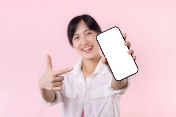 快乐的笑着的亚洲年轻女性推荐展示新的应用程序或移动广告 模仿被粉色背景隔离的智能手机模板 大写字母空白屏幕数字移动设备 — 图库照片